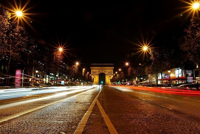 Traffic trails down the Champs-&Eacute;lys&eacute;es with the Arc de Triomphe lit at the end