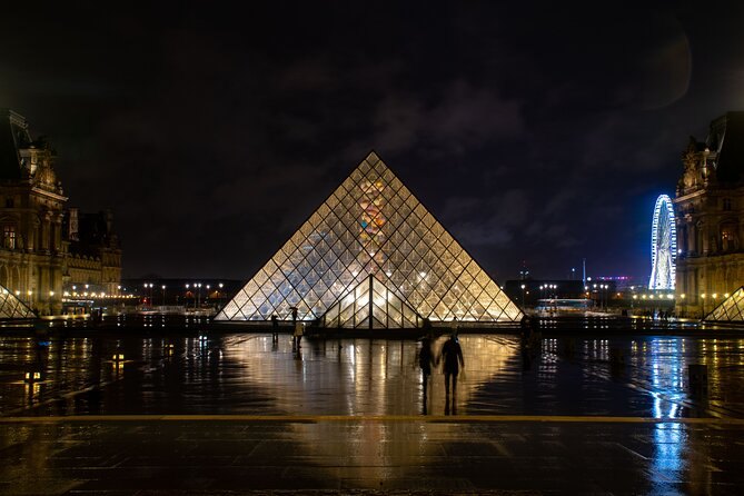 The Louvre pyramid mirrored in the courtyard basins at night