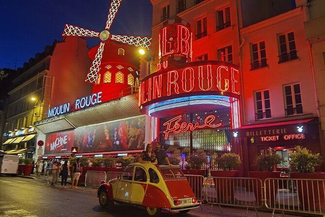 The Moulin Rouge sign glowing red at the foot of Montmartre