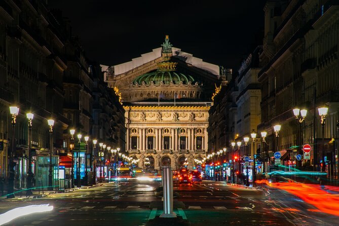 The Palais Garnier lit along its facade with the boulevard busy in front